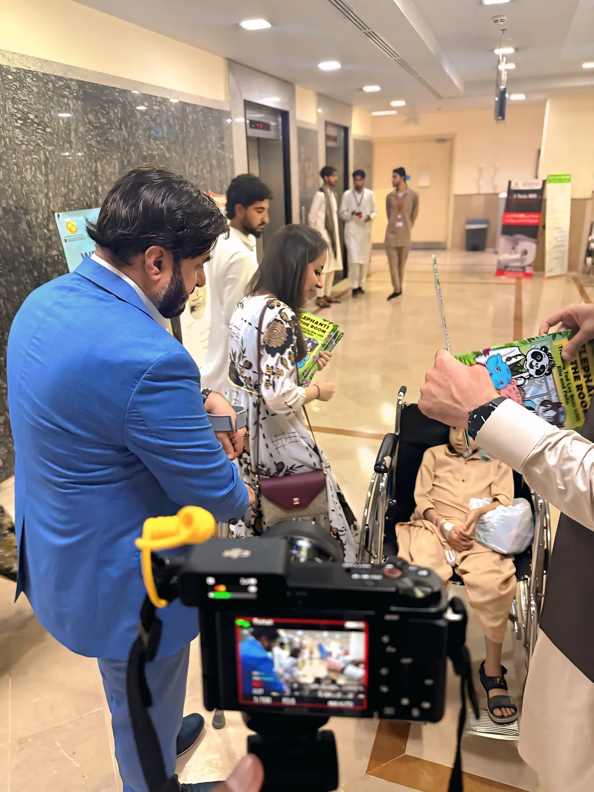 The team bringing comics along the ward corridor, filmed for the charity's record of the visit.