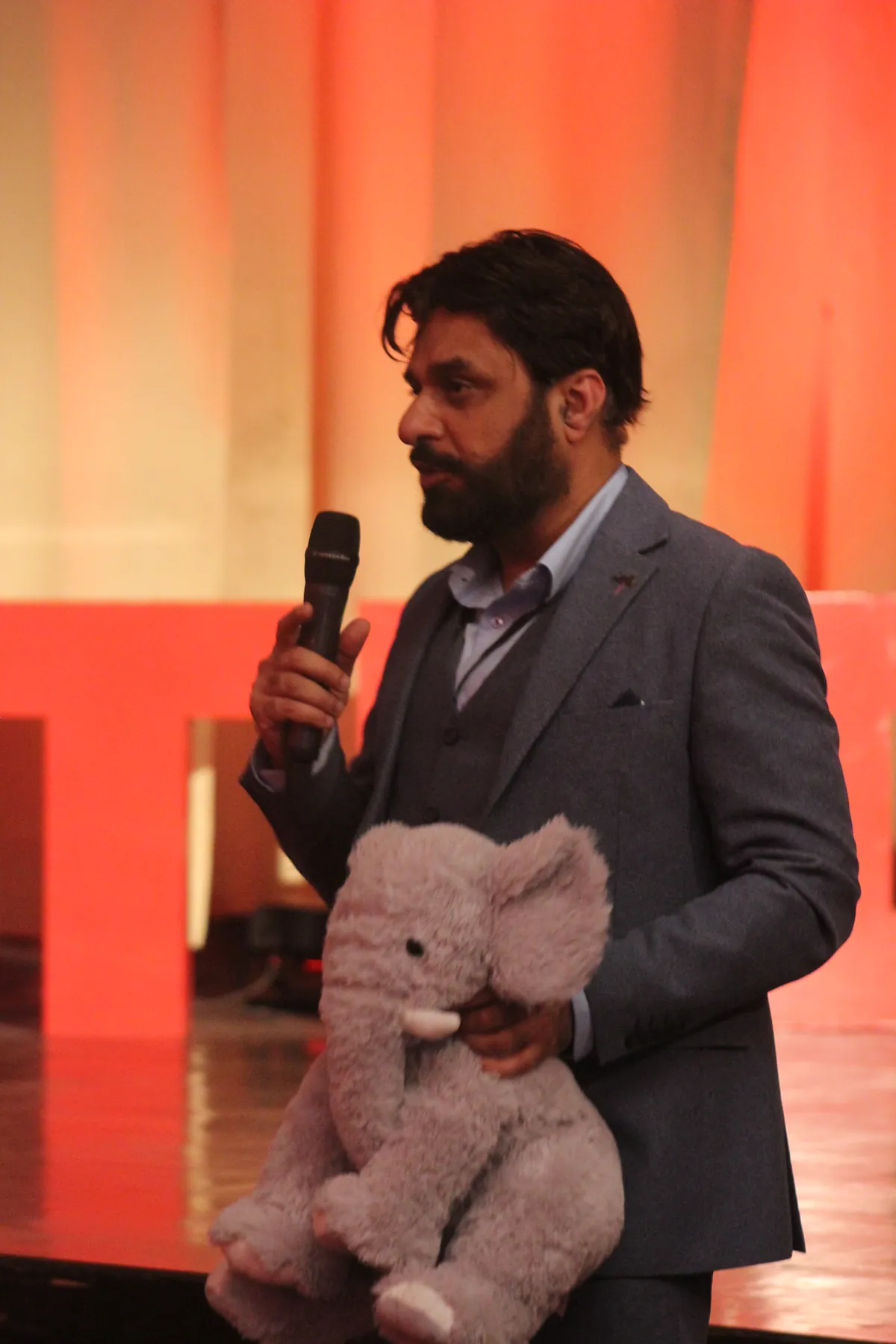 Dr Mohammad Muneeb Khan speaking into a handheld microphone on the TEDx stage.