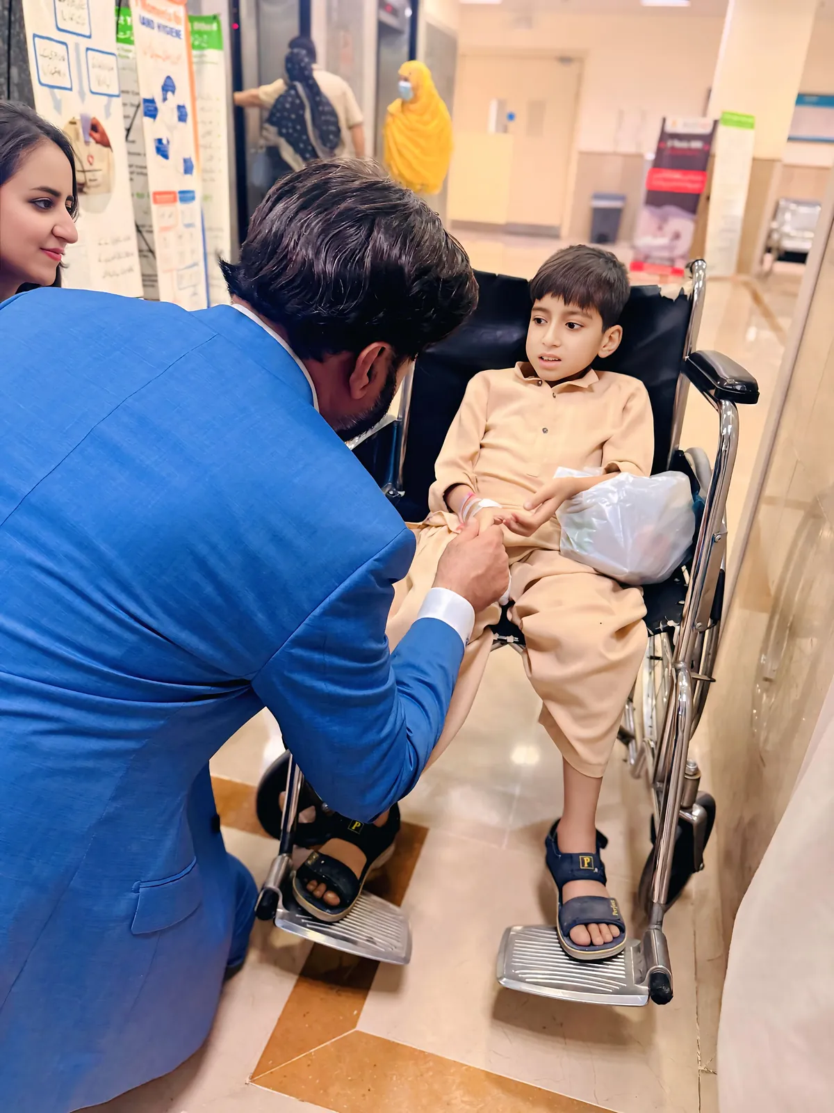 Dr Khan crouching to talk with a young reader on the children's ward.