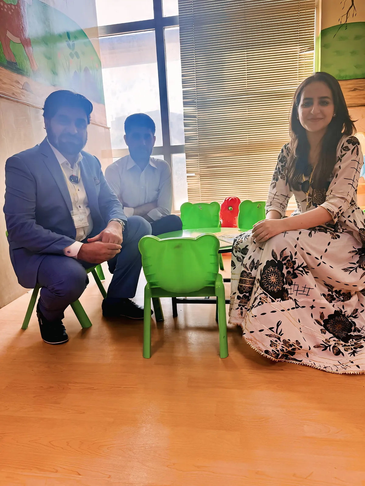 The team sitting on the small chairs of the hospital play area, reading with children and their families.