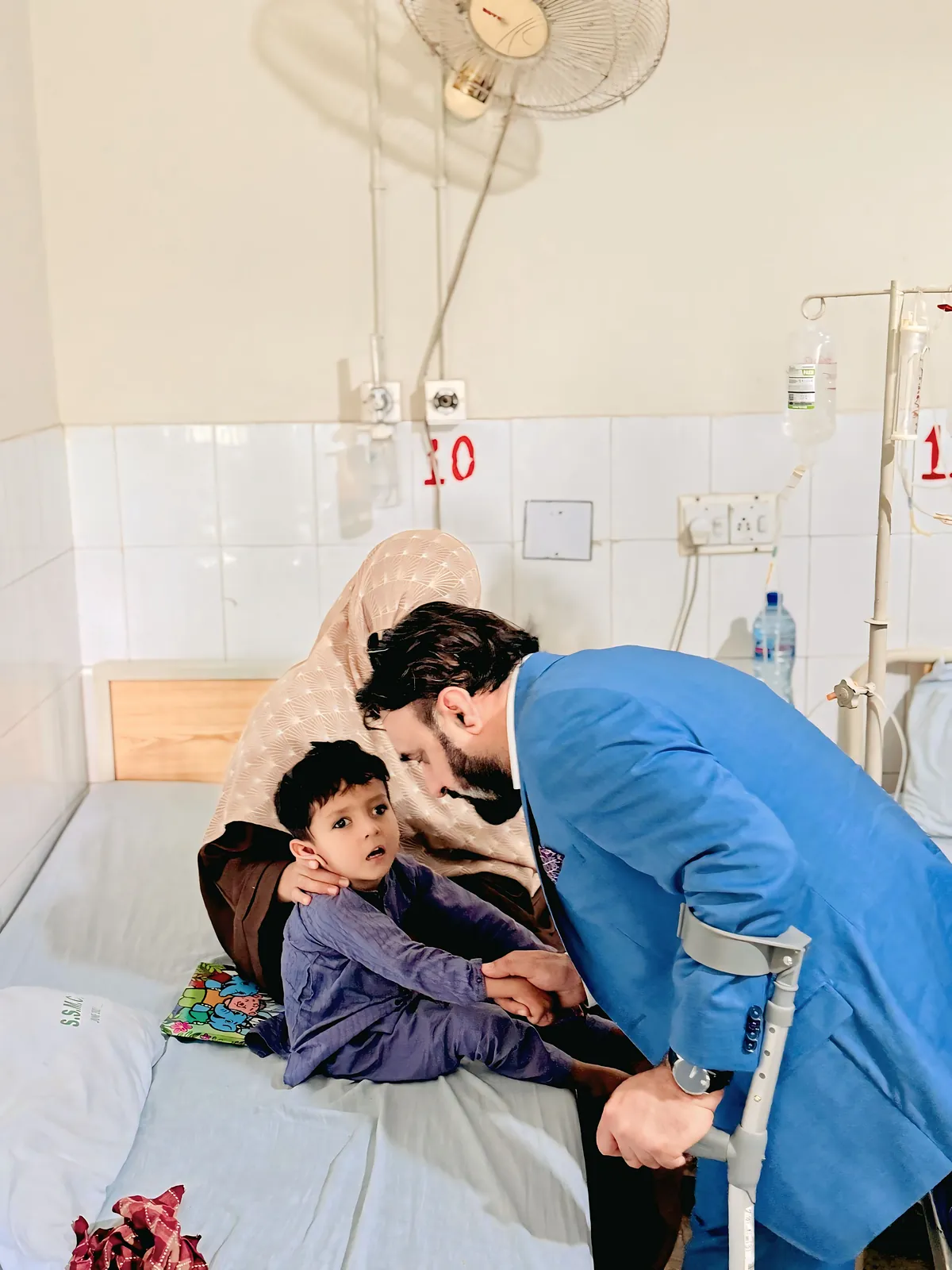 Dr Khan leaning in to read a page of the comic with a child and their parent.