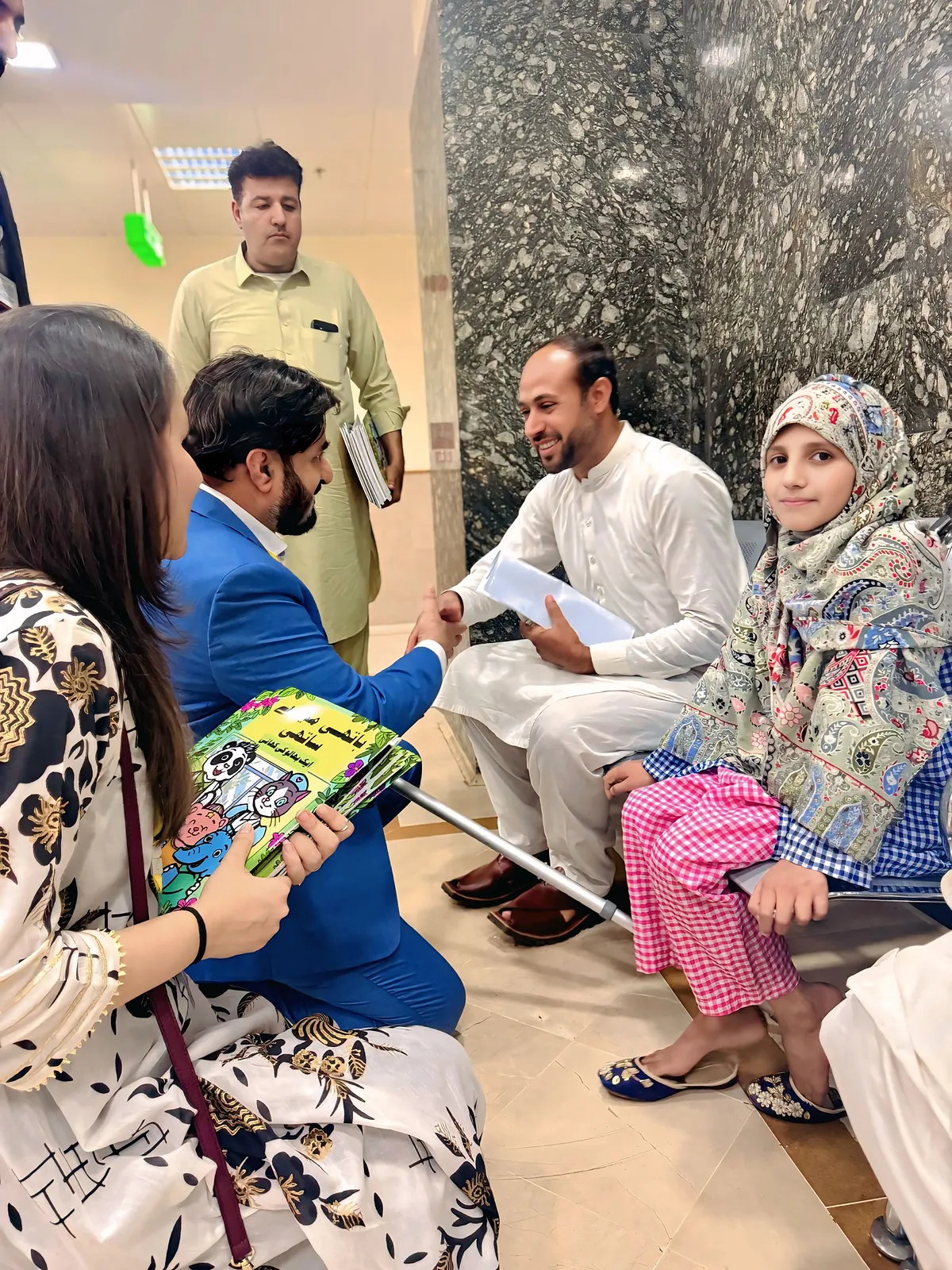 Members of the team sitting with a family, showing them a copy of the comic.