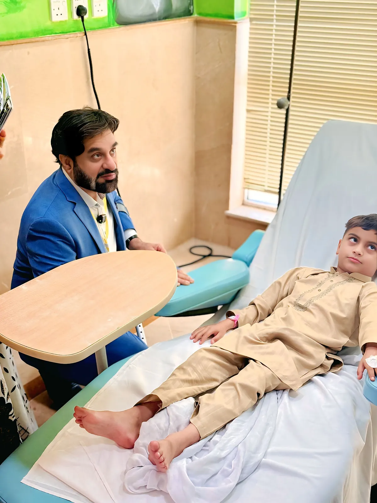Dr Khan sitting with a young reader during the visit to the children's ward.